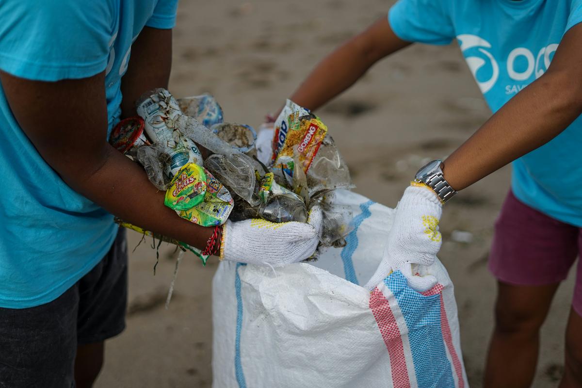 Volunteers in gloves collecting plastic from a beach